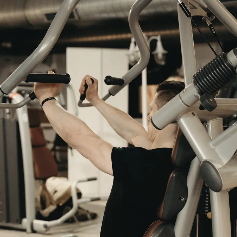 Person an einer Brustpresse im Trainingsstudio