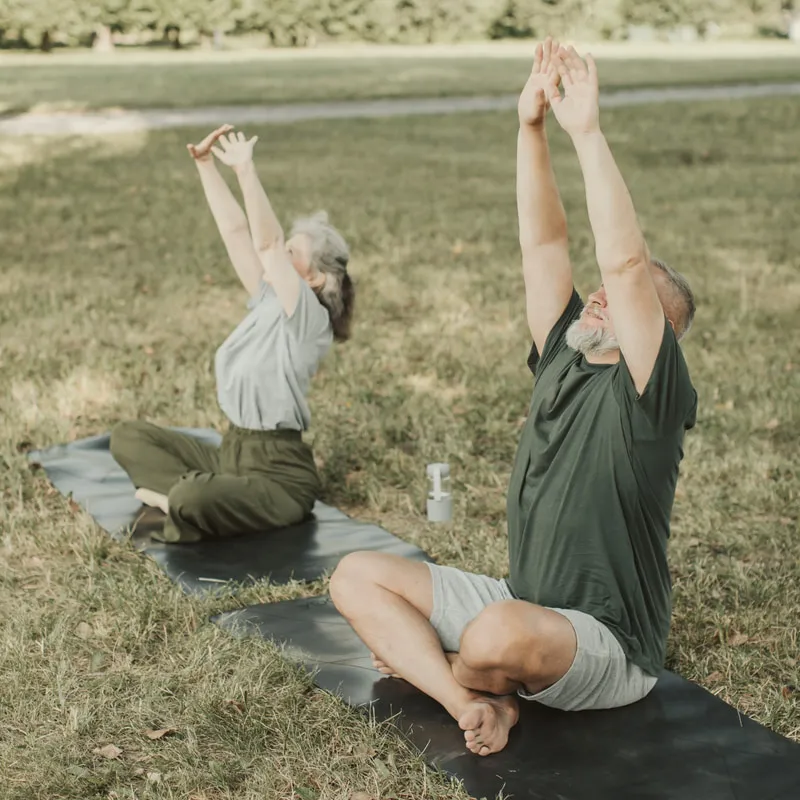 Älteres Paar bei Yoga-Übungen auf Matten im Park